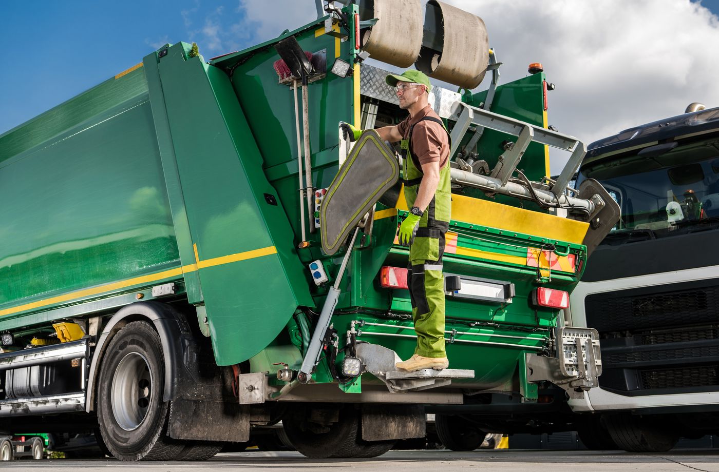 Crew member stepping onto a green junk removal truck